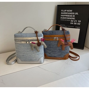 Dettaglio delle borse in denim con manici in pelle e ciondoli decorativi a cavallo
