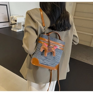 Dettaglio della borsa a secchiello in denim blu con ciondolo a cavallo in pelle marrone