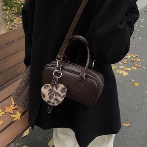 Vintage dark brown bowling shoulder bag with leopard heart charm in autumn park setting