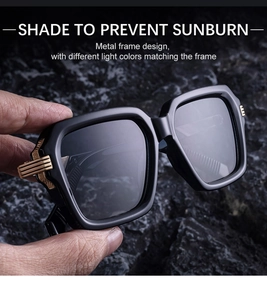 Details einer eckigen schwarzen Sonnenbrille mit goldener Verzierung auf dunklem Fels