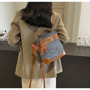 Dettaglio della borsa squadrata in denim retrò con finiture in pelle e ciondolo