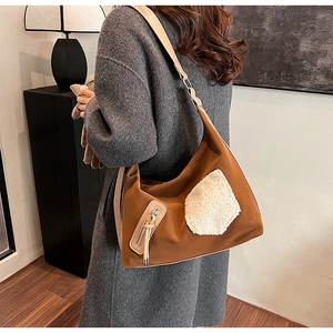 Brown nylon shoulder bag featuring white plush pocket detail on side worn by model