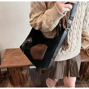 Detail of vintage hobo bag with brown suede patch and decorative tassel on shoulder strap