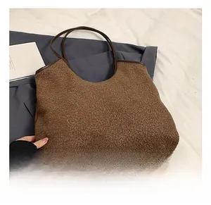 Detail of dark brown faux shearling tote bag with textured plush fabric and leather handles