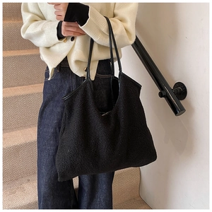 Detail van de grote zwarte lamswol tote tas met slanke schouderbanden voor dames