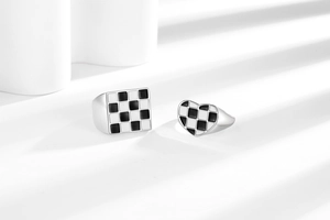 Detail of checkerboard enamel heart and square rings with geometric light and shadow