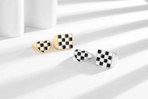 Detailed view of checkered heart and square rings with polished gold and silver finish