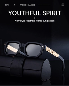 Detail of black rectangle sunglasses with gold arrow metal accents and leather case