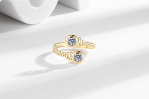 Macro detail of gold-plated twisted rope ring featuring two sparkling round-cut crystals