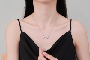 Detail of evil eye necklace with hugging hands pendant on woman in black dress