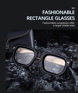 Detail of square black sunglasses with metallic T-shaped accents on dark textured rocks