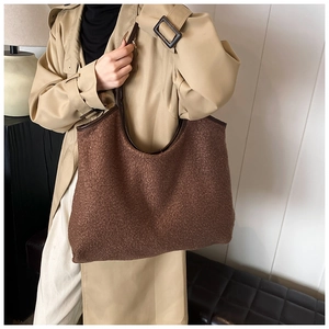 Close-up of brown plush tote bag texture with dark leather straps on a model
