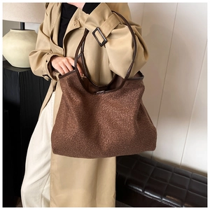 Brown lamb wool tote bag with leather handles shown on a model in a trench coat