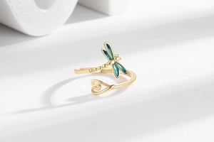 Macro detail of golden dragonfly ring with blue enamel wings and polished heart finish