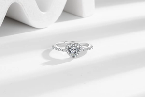 Makroaufnahme eines silbernen Herz-Zirkonia-Rings mit verstellbarem, offenem Ringband