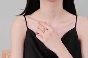 Detail shot of a silver dragonfly ring with blue enamel worn by a model in black