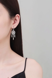 Detail of dreamcatcher earrings with colorful stones and silver feather tassels on a model
