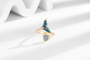 Detailed macro view of gold fish tail ring with blue enamel and heart-shaped zircon gemstone