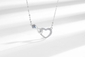 Detail of silver infinity heart necklace with crystal pendant on elegant white background