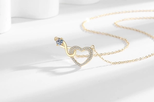 Detailed view of infinity heart necklace pendant with sparkling crystals on gold chain
