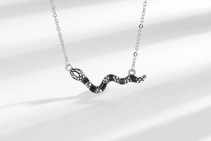 Dettaglio ravvicinato di un ciondolo a forma di serpente vintage con smalto nero e catena