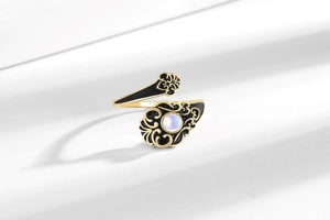 Detail of vintage gold open ring with moonstone inlay and black enamel patterns