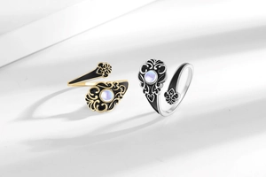 Macro shot of vintage open rings with white opal inlay and ornate floral engravings