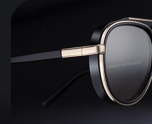 Detail view of black and gold pilot sunglasses with metal hinges and gradient lenses
