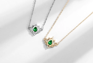 Detail of silver and gold lotus necklaces featuring tear-drop green gemstones on simple chains