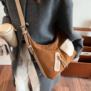 Brown frosted leather tote bag with white fleece pocket detail worn over a grey coat