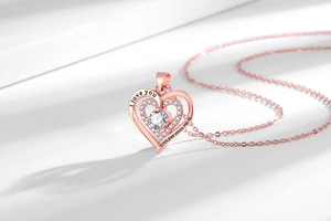 Dettaglio del ciondolo a doppio cuore in oro rosa con incisione I love you to the moon and back