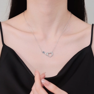 Silver infinity heart necklace with blue gemstone and pavé diamonds worn by model