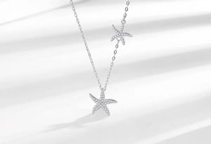 Détail macro du collier double étoile de mer en argent avec cristaux pavés sur chaîne