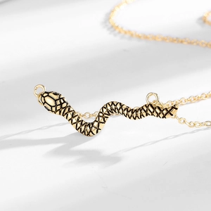 Collana vintage con pendente a serpente dorato e trama in smalto nero su sfondo bianco