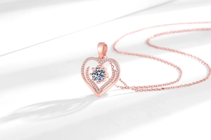 Dettaglio della collana a cuore con finitura oro rosa e intarsio di gemma centrale