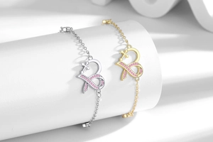 Detail of silver and gold heart bracelets with pink pavé ribbon cross on pedestals