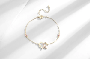 Detailed view of a gold heart bracelet with pink zircon ribbon and adjustable clasp
