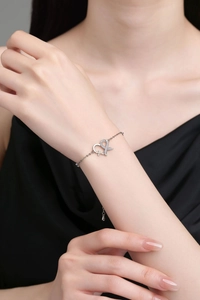 Close-up of heart and bow charm bracelet with sparkling zircons on a model's wrist