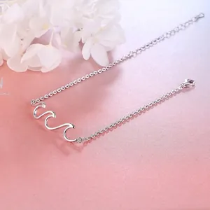 Minimalist S925 silver wave bracelet with crystal accents on textured pink background