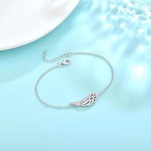 Elegant silver angel wing bracelet with sparkling pink crystals on a water wave background