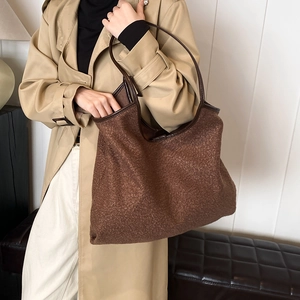 Bruine fleece tote tas met leren hengsels gedragen door model in trenchcoat