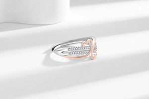 Close-up of interlocking silver and rose gold hearts ring set with cubic zirconia stones