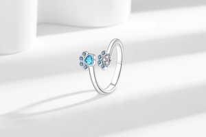 Macro view of adjustable silver pet paw ring with heart-shaped blue zircon stone