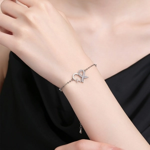 Silver heart and bowknot bracelet with sparkling zircons on a female wrist