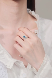 Detailed view of silver pet paw ring with blue heart zircon on a model hand