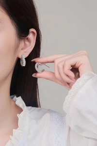 Close-up of heart-shaped silver C-hoop earrings with pave-set rectangular zircons