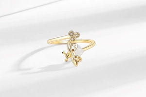 Close-up of golden honeybee ring featuring open honeycomb design and white pearl detail
