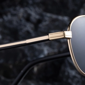 Macro shot of gold metal hinges and black temples of trendy oval sunglasses