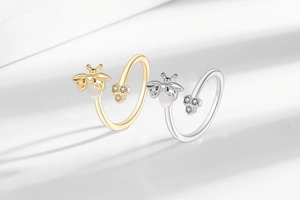 Detail of bee and honeycomb rings with moonstone-like wings in gold and silver