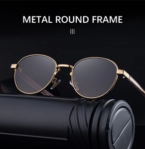 Close-up of golden metal round frame sunglasses with dark lenses on a black pedestal